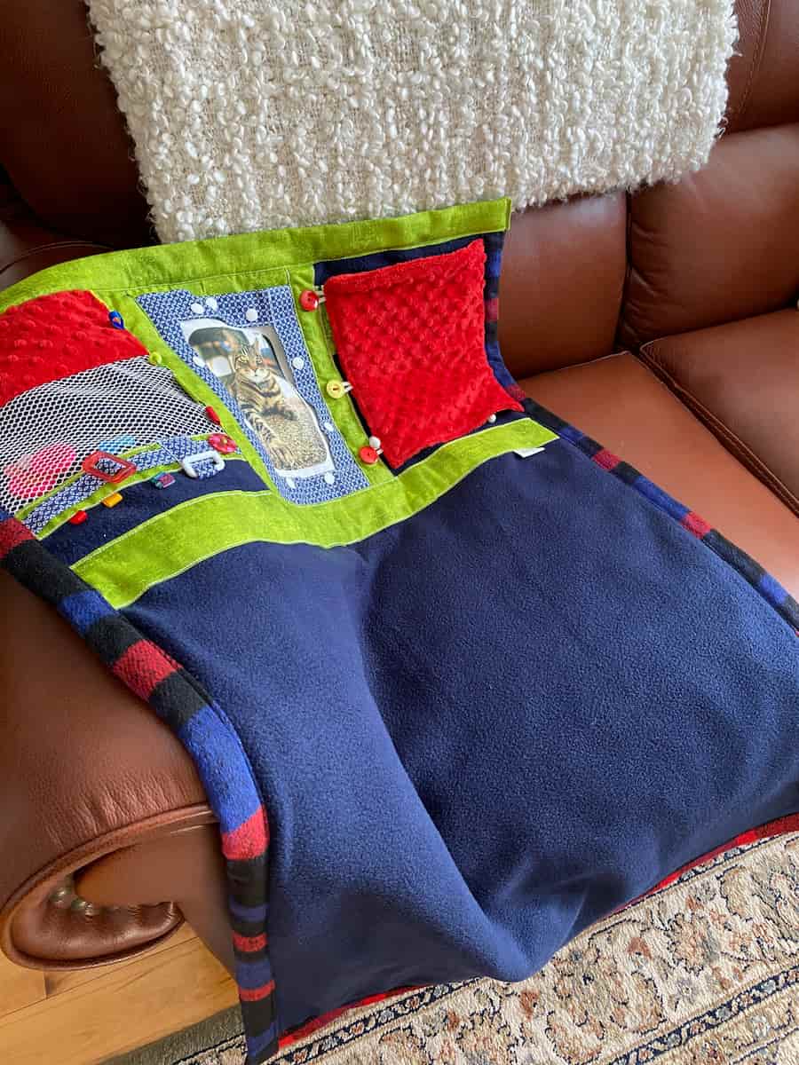 couverture bleu, verte et rouge avec chat sur divan, blue, green and red blanket with cat on couch