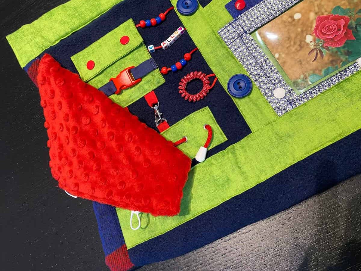 couverture bleu, verte et rouge vue rapprochée fleur et panneau d'activités, blue, green and red blanket close-up view flower and activity panel