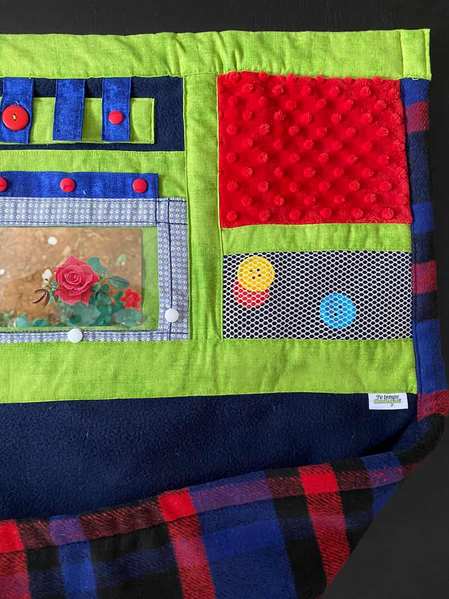 couverture bleu, verte et rouge vue rapprochée fleur et pochette, blue, green and red blanket close-up view flower and pouch