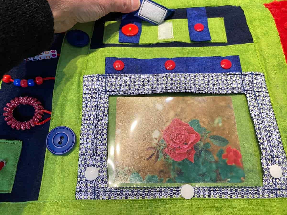 couverture bleu, verte et rouge vue rapprochée fleur et velcro, blue, green and red blanket close-up view flower and velcro